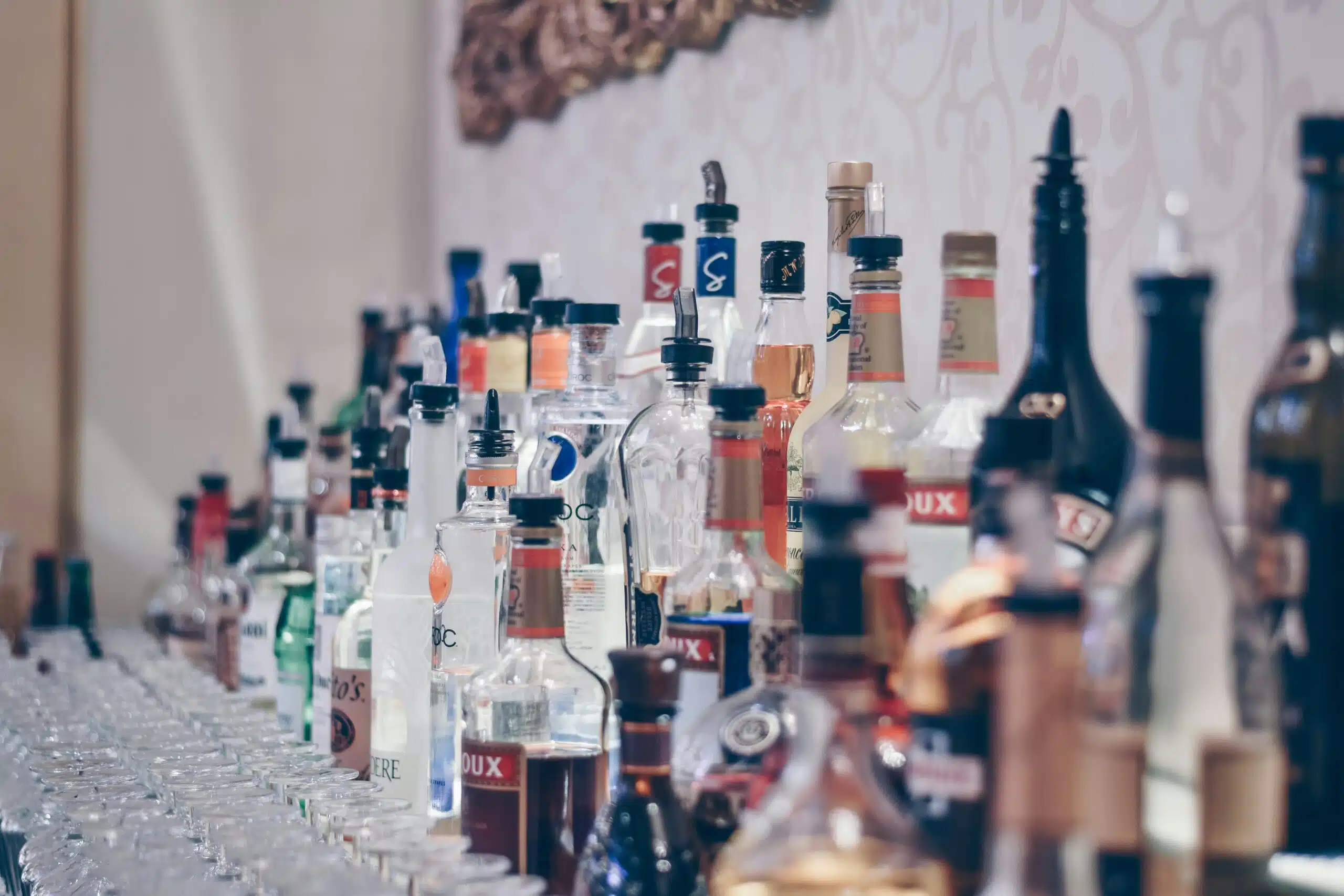 Array of colorful liquor bottles displayed on a bar counter, showcasing eco-friendly beverage service options for events and enhancing guest experiences.