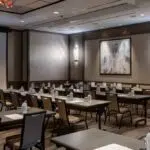 a modern corporate conference room features a sleek, high-definition projector displaying a vibrant presentation on a large screen, surrounded by polished glass tables and ergonomic chairs, illuminated by focused spotlights that enhance the professional atmosphere.