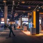 a vibrant trade show booth bustling with attendees, showcasing strategically placed, eye-catching signage and elegant easels that highlight the latest innovations, all illuminated by dynamic spotlights in a modern indoor convention center.