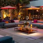 a chic outdoor party setup featuring elegant heaters, stylish fans, and colorful umbrellas, all arranged on a sleek patio with modern furniture, illuminated by ambient lighting to create a vibrant atmosphere.