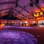 a dynamic and strategically organized exhibition space showcases an innovative tent layout, featuring engaging areas for interaction and seamless flow, illuminated by bright, focused artificial lighting that enhances the modern atmosphere.