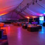 a dynamic indoor event space showcases a sleek, modern tent equipped with sophisticated climate control systems, highlighting the contrast between a vibrant, bustling atmosphere and advanced technology managing both warmth and coolness, illuminated by soft, ambient lighting.