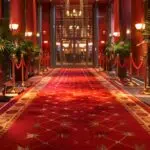 an elegant event space featuring plush red carpets, opulent velvet ropes, and glamorous lighting, creating a sophisticated vip section that exudes luxury and exclusivity.