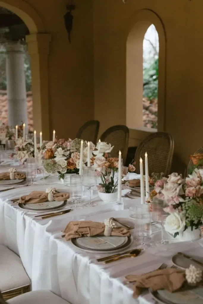 Intimate dining table with floral centerpieces and candles for a cozy venue setup.
