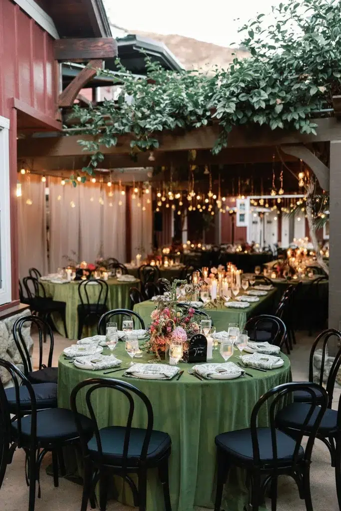 Elegant holiday dinner setup with green table linens, candlelight, and warm string lighting.
