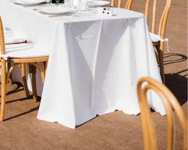 White tablecloth draping a banquet table with rustic Bentwood Natural Chairs, set for an elegant outdoor wedding at Tuscan Hills Estate.