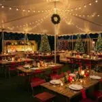 Festive outdoor holiday event setup with decorated tent, elegant table settings, and seasonal decor