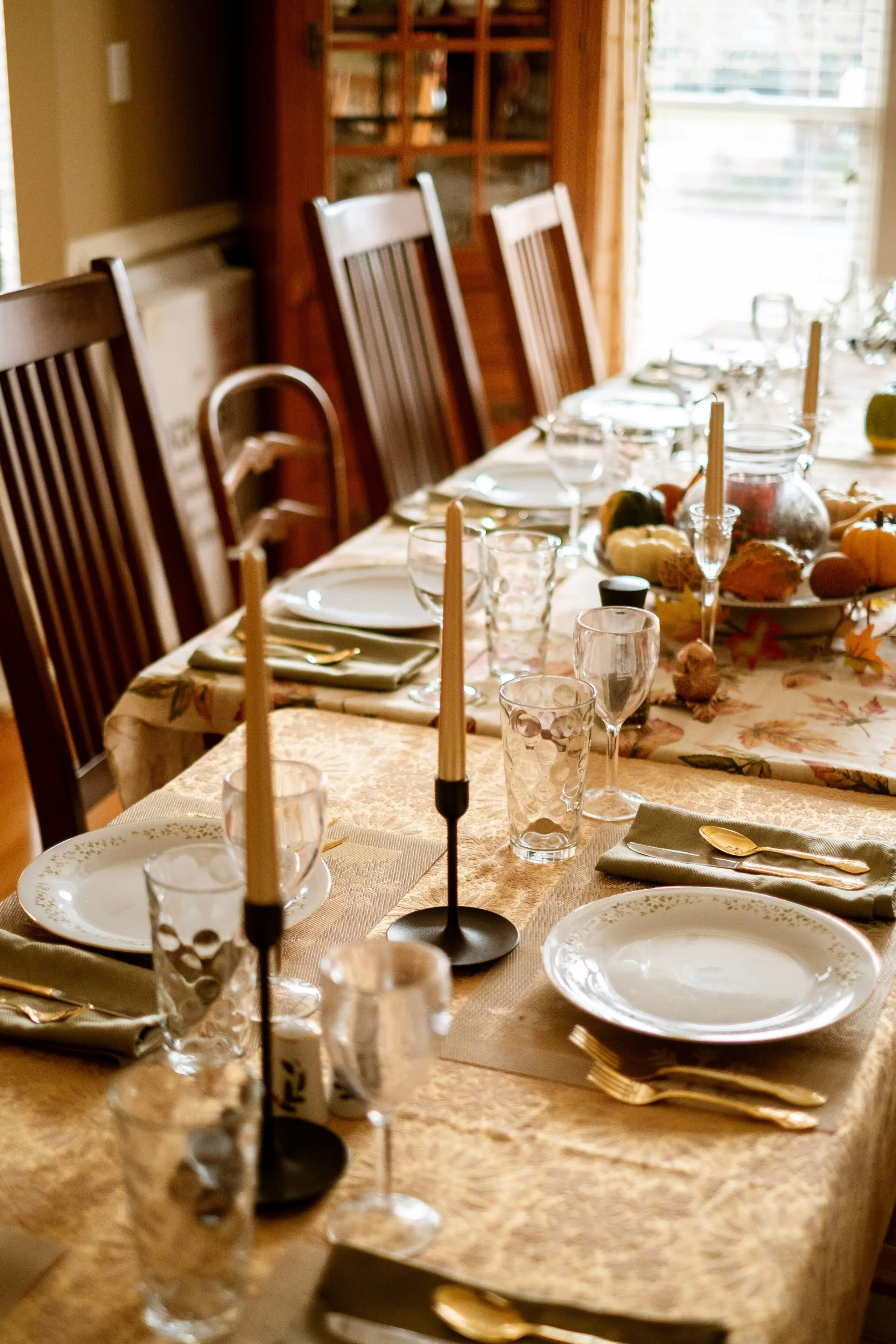 Elegant dining setup with gold-accented tableware, glassware, and tapered candles, reflecting a warm, inviting atmosphere for holiday celebrations.