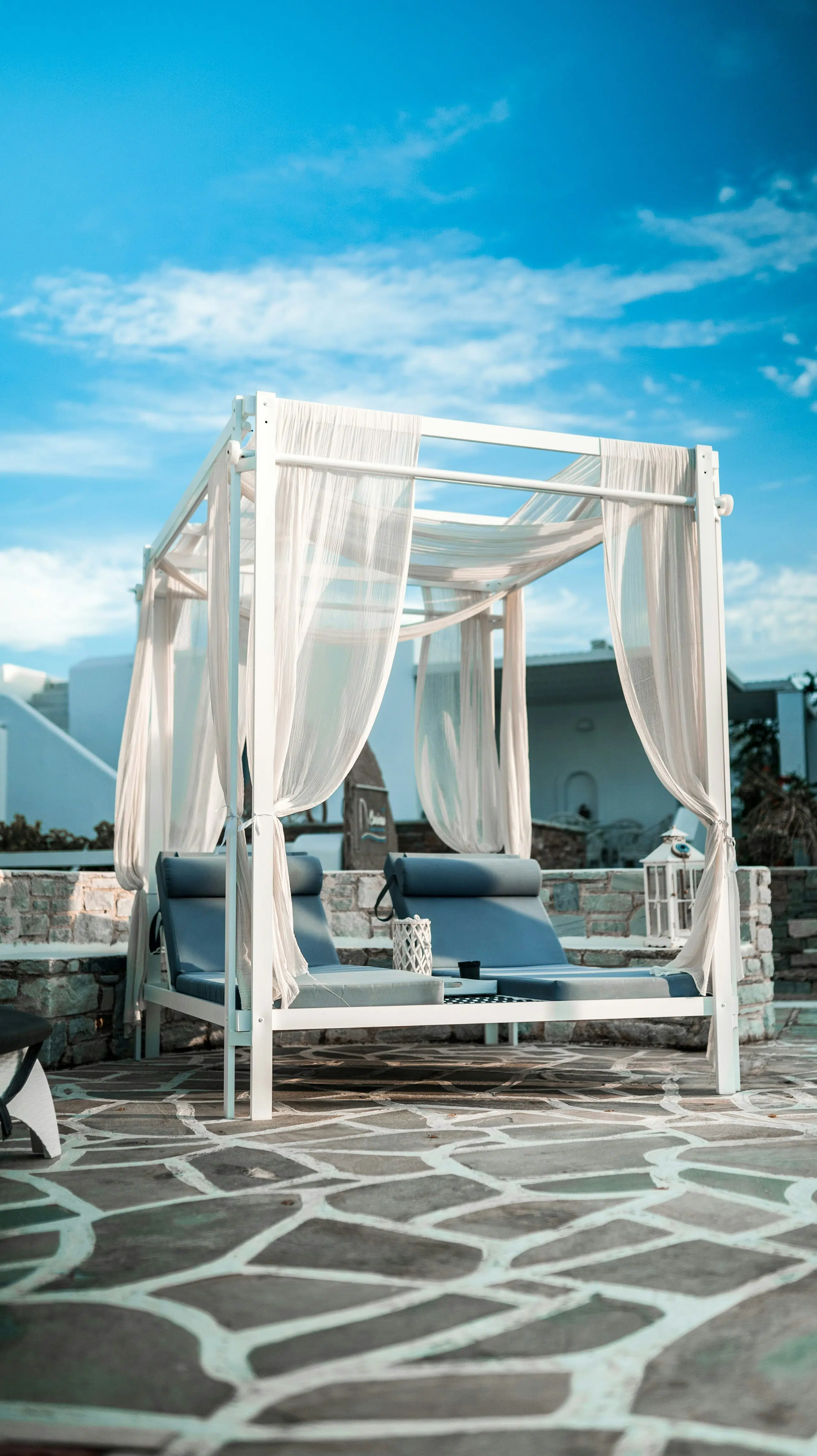 Luxury lounge furniture with a white canopy and blue cushions, set against a clear sky, creating an inviting atmosphere for Southern California holiday celebrations.