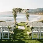 Outdoor wedding setup in Ventura with chairs and floral arch, highlighting essential rental elements