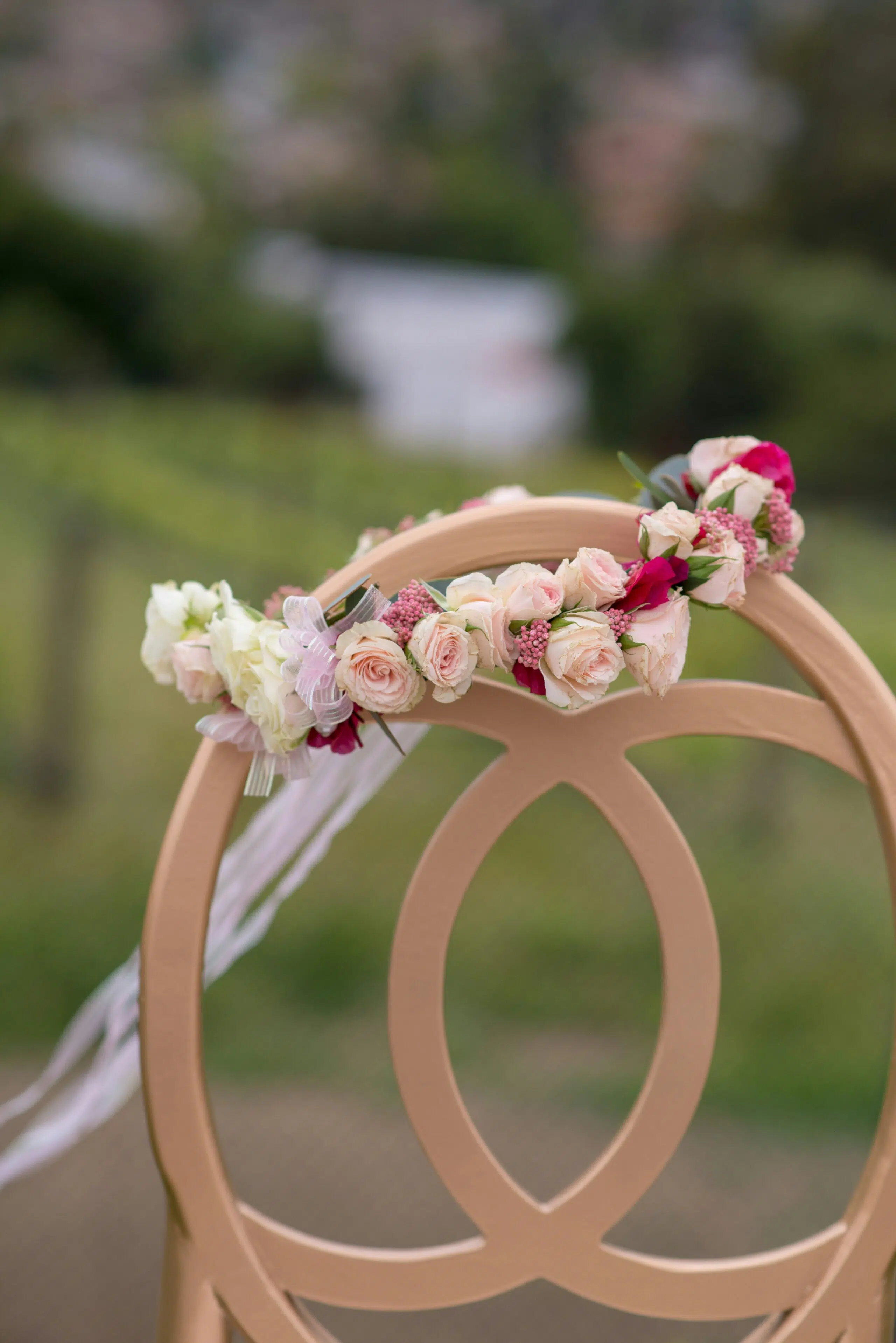 Floral arrangement on a decorative chair, featuring pink and white roses, set against a blurred vineyard backdrop, ideal for California weddings and events.