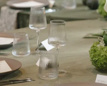 Verona Ridged Glassware on a green tablecloth, complementing a romantic wedding setting at Hotel San Buena, featuring elegant place settings with soft textures and understated decor.