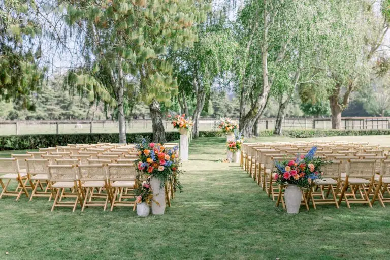 Elegant outdoor wedding ceremony setup with wooden chairs, vibrant floral arrangements, and lush greenery at a scenic venue, ideal for romantic celebrations in Santa Barbara.