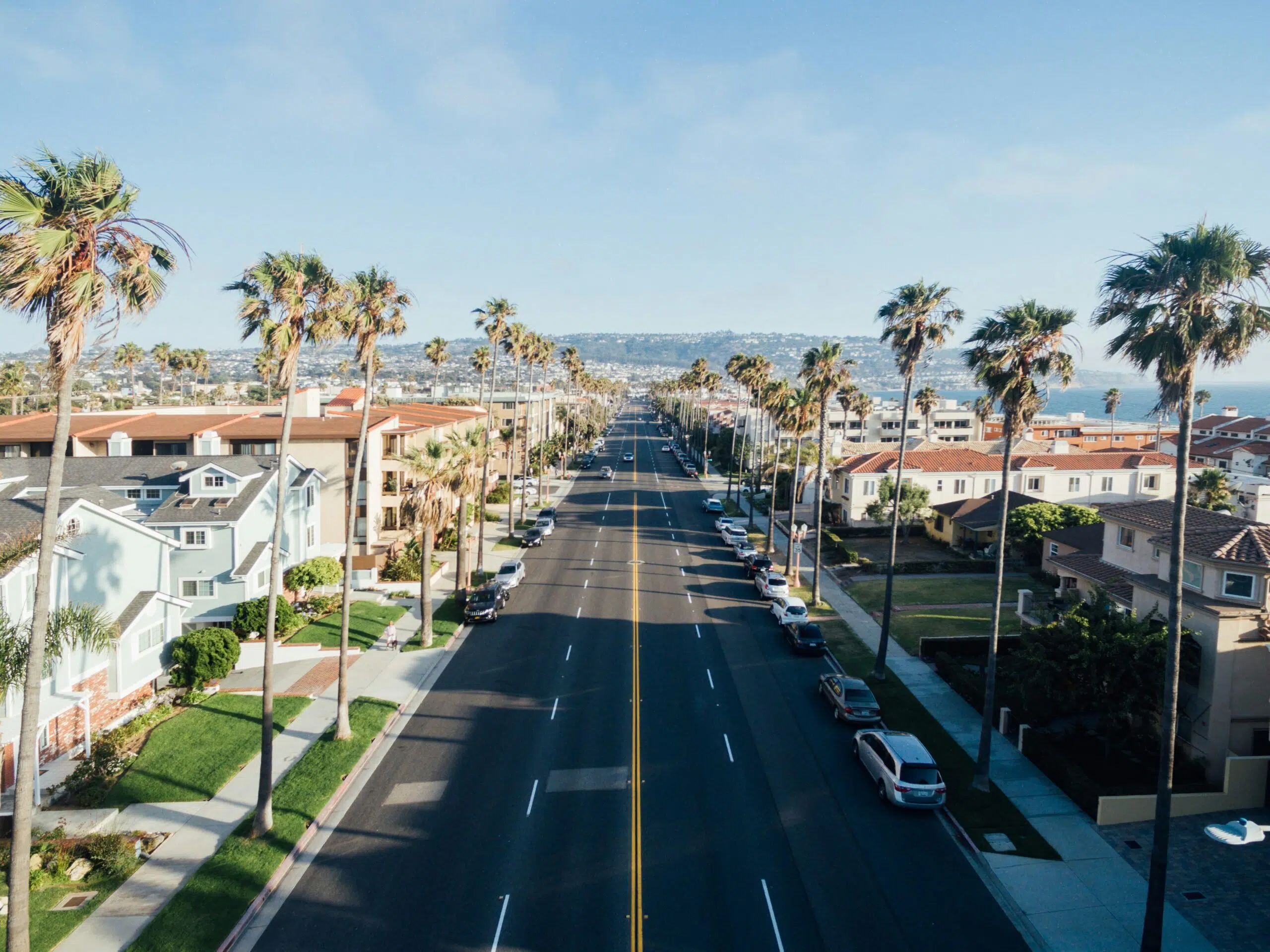 California coastal street lined with palm trees, residential buildings, and ocean view, illustrating a sunny outdoor setting ideal for traditional tent events.