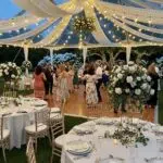 Outdoor wedding tent with a wooden dance floor and guests dancing joyfully