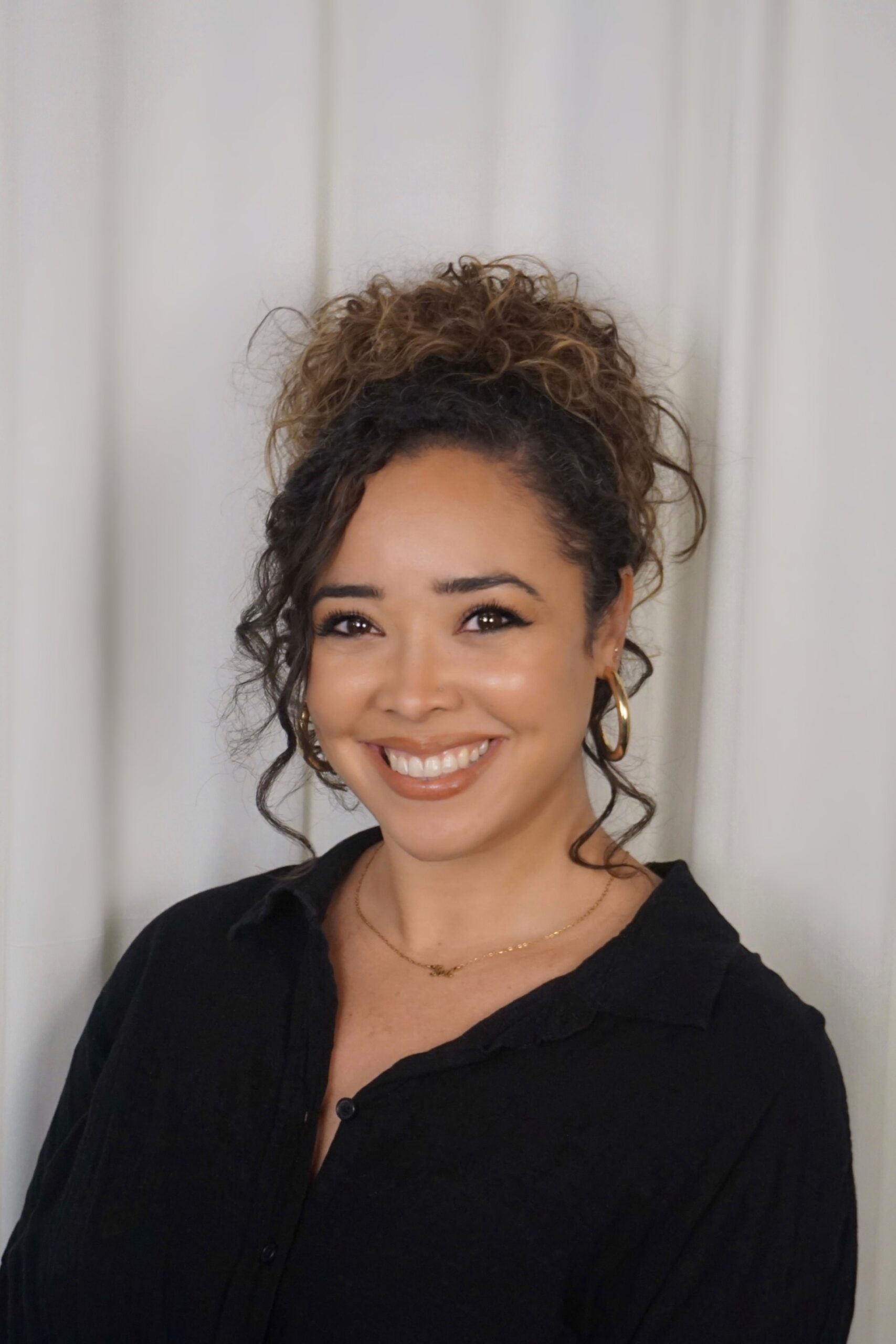Smiling team member of Ventura Rentals, wearing a black shirt and gold jewelry, against a light background.