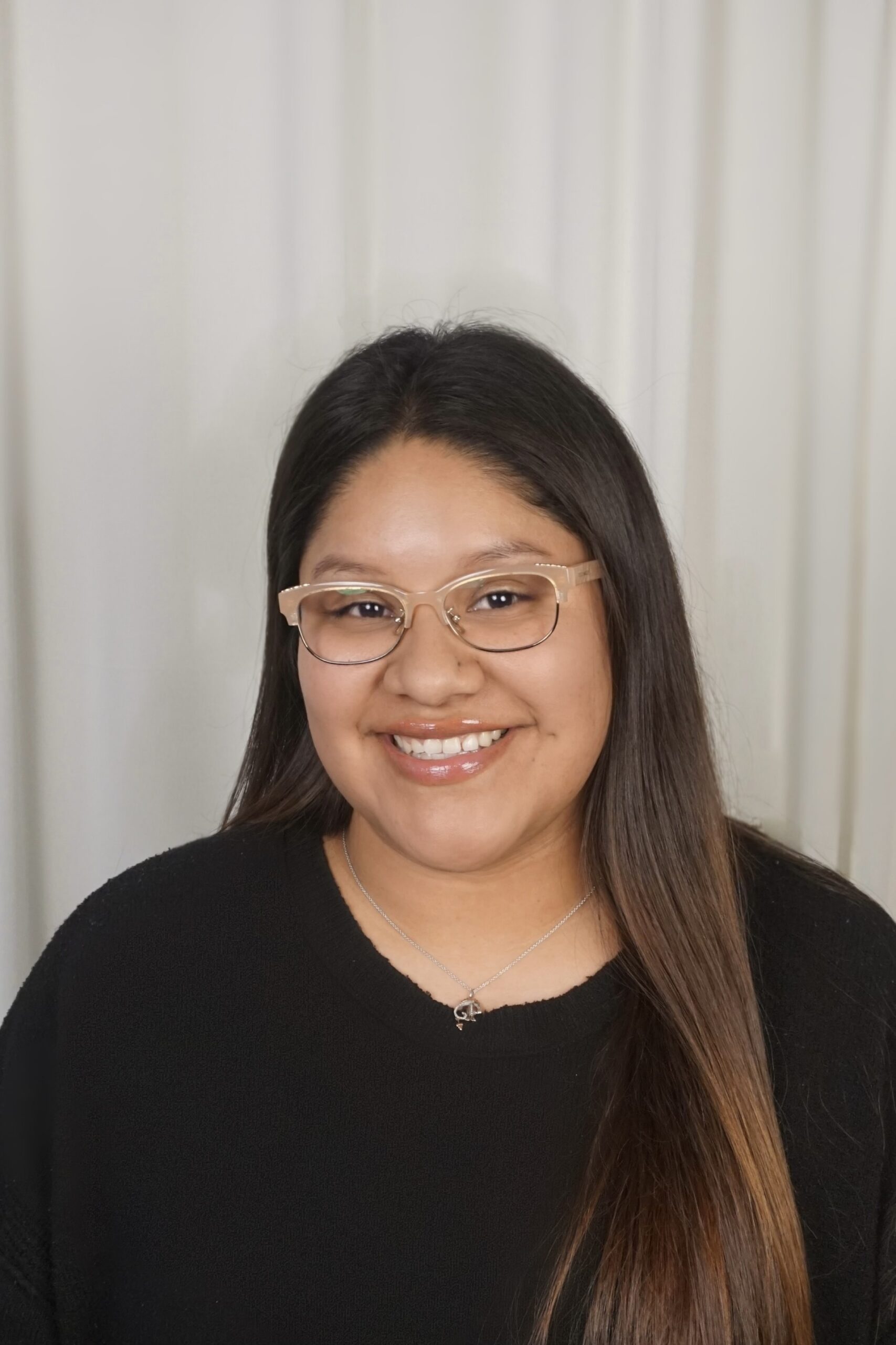 Smiling woman with long hair wearing glasses and a black sweater, representing the team at Ventura Rentals.