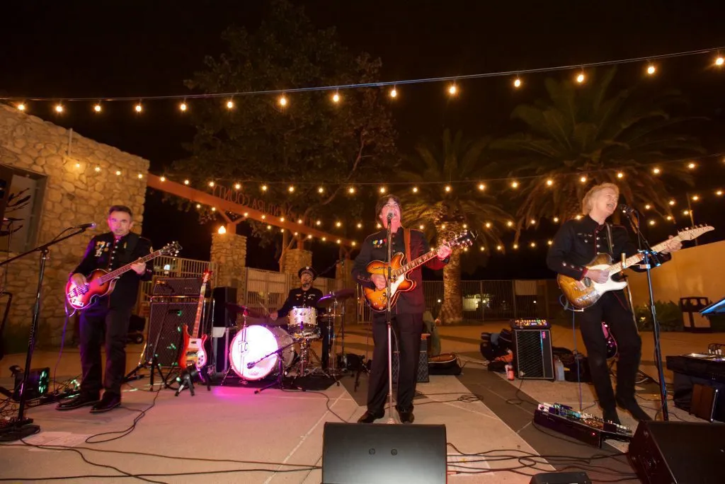Live band performing on an outdoor event stage with production equipment