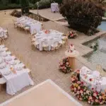 Elegant outdoor event setup with tables, floral arrangements, and a cake
