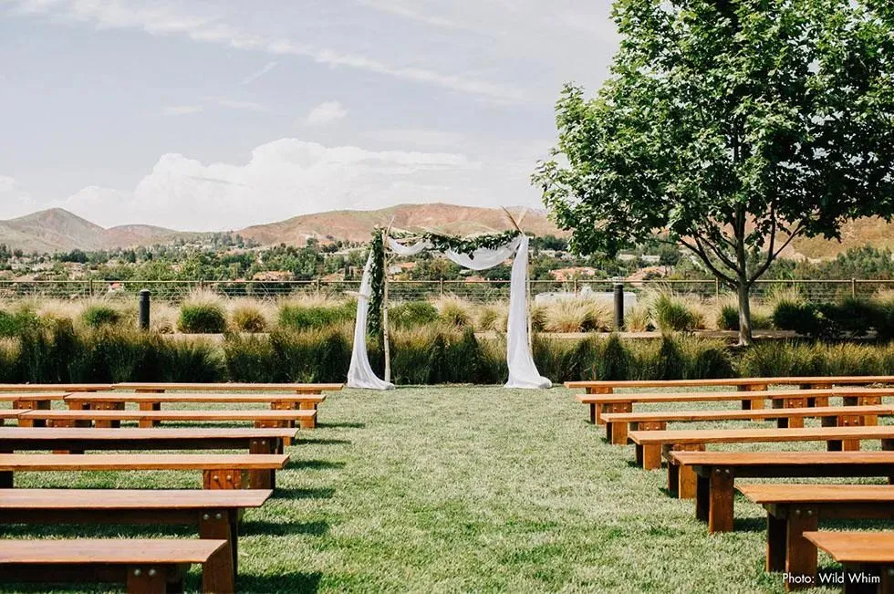 Outdoor wedding venue with wooden benches and a floral arch
